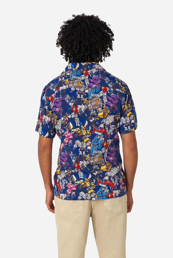 Person wearing a colorful Transformers patterned shirt on a white background. View from the back.