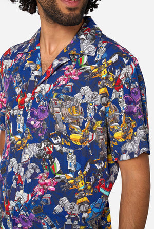 Man wearing a colorful Transformers robot patterned shirt on a white background
