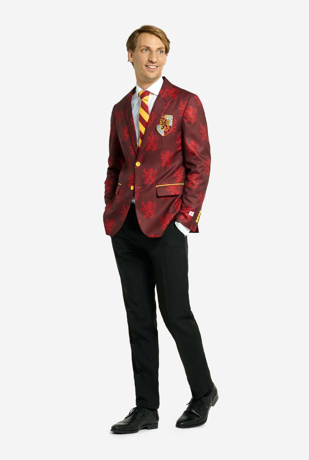 Image with light grey background and man wearing Harry Potter suit, Gryffindor styled. Suit consists of red blazer with Gryffindor logo and light red lions all over print, black pants, and red and yellow diagonal striped tie.     
