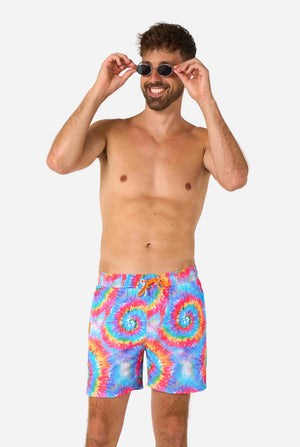 Man wearing colorful tie-dye swim shorts on a white background
