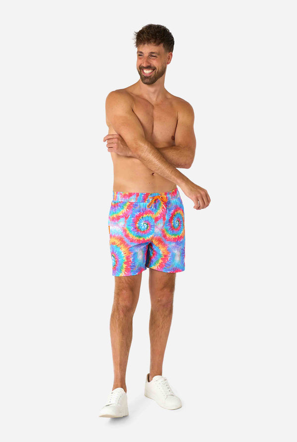 Man wearing colorful tie-dye swim shorts on a white background. Full body image