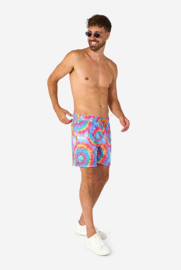 Man wearing colorful tie-dye swim shorts on a white background. Full body image
