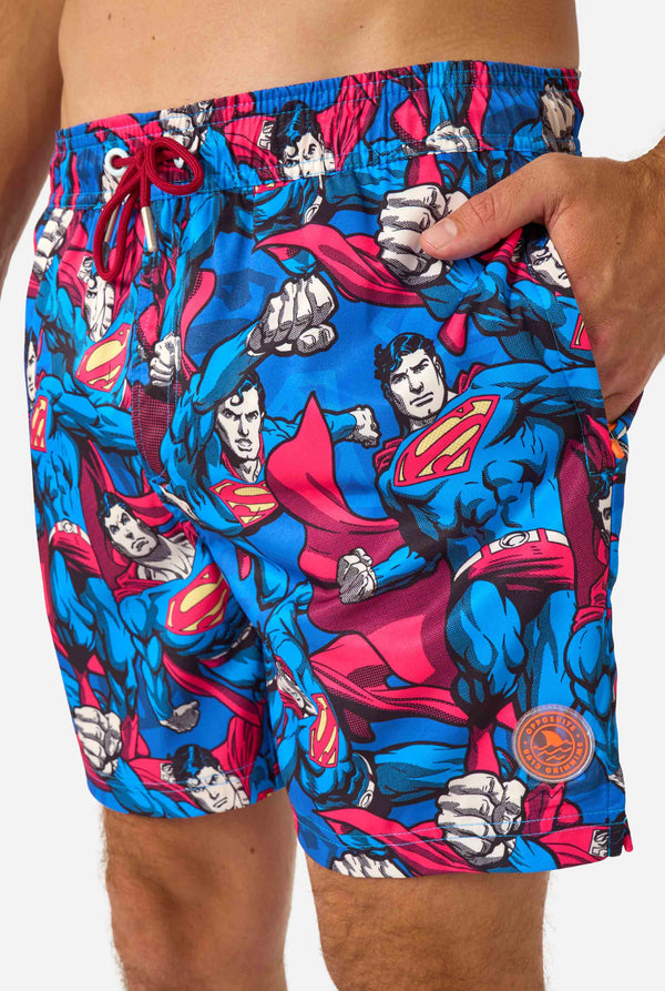 Superman-themed swim shorts with a visible brand logo on a white background