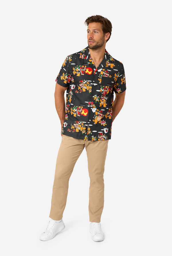 Man wearing a colorful patterned Bowser shirt and beige pants on a white background