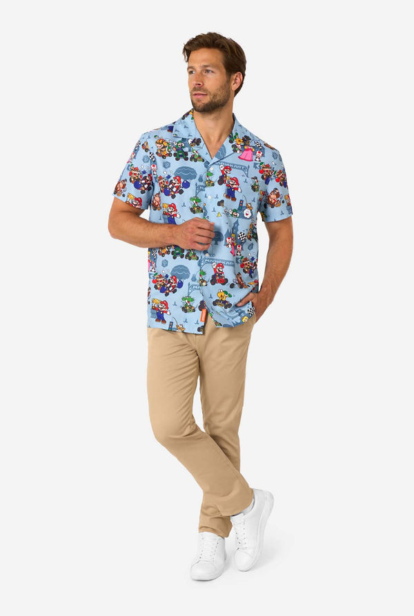 Man wearing a colorful patterned Mario shirt with beige pants on a white background