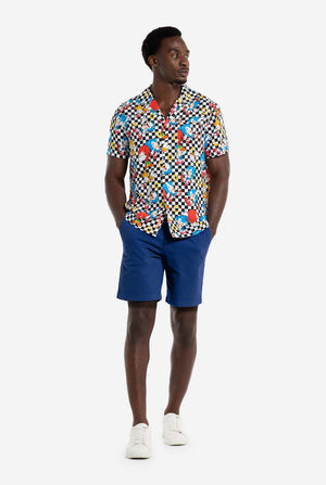Man wearing a colorful patterned Sonic shirt and blue shorts on a white background. Full body image