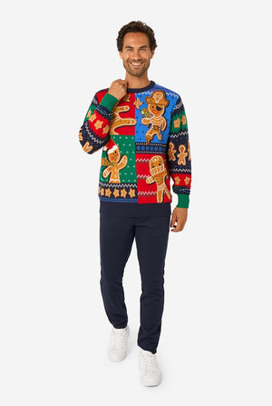 Man wearing a colorful Christmas sweater with gingerbread men design on a white background. Full body image