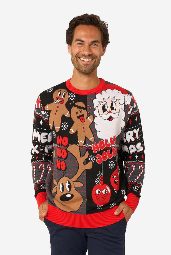 A man modeling a black Christmas crewneck sweater with colorful holiday graphics including gingerbread men, Santa, a reindeer, and 'Holly, No, Holly' text, paired with navy pants against a light gray studio background.