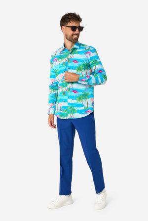 A man wearing a colorful tropical shirt and blue pants on a white background, also wearing sunglasses.