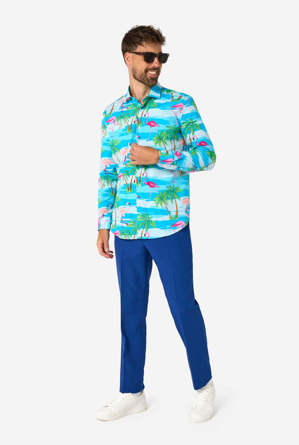 A man wearing a colorful tropical shirt and blue pants on a white background, also wearing sunglasses.