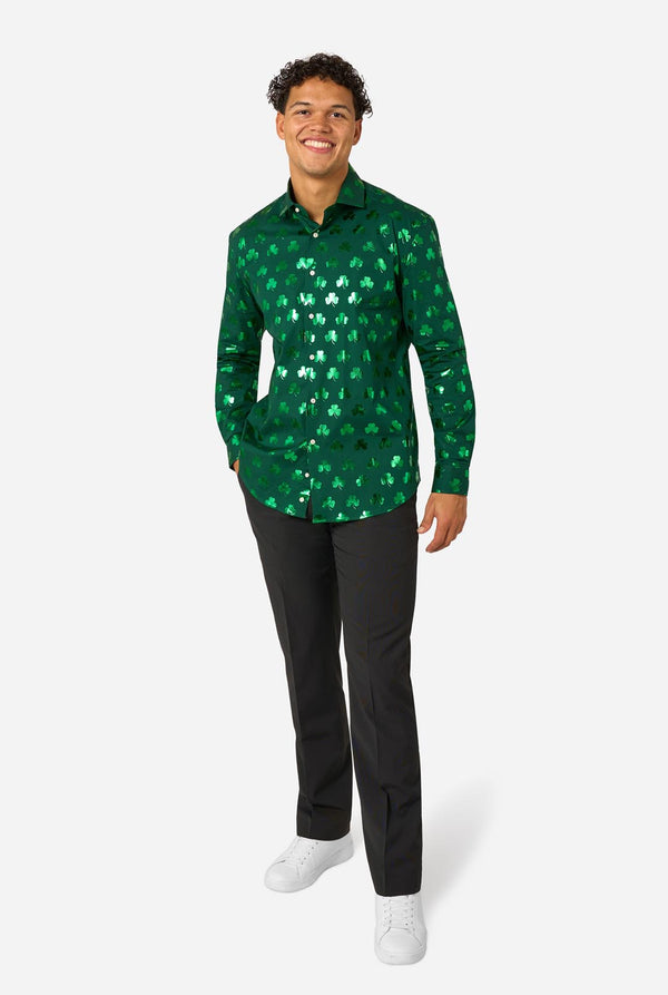 Man wearing a green patterned shirt and black pants on a white background. Full body image