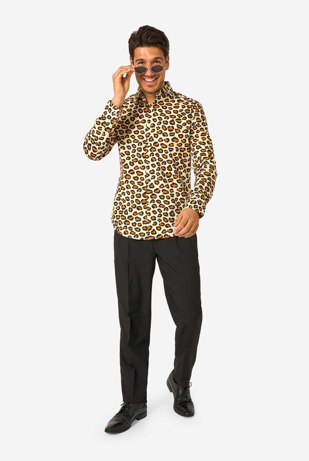 Image of a man wearing a beige shirt covered with panther spots, and wearing black pants. 