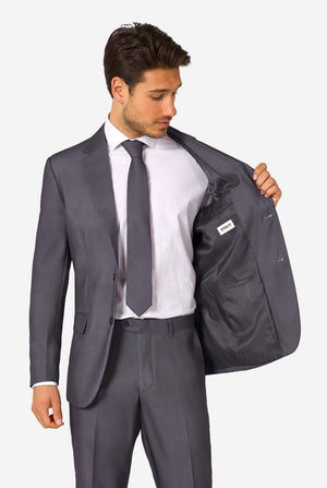 Man wearing a gray suit with a white shirt and tie, holding his jacket open.