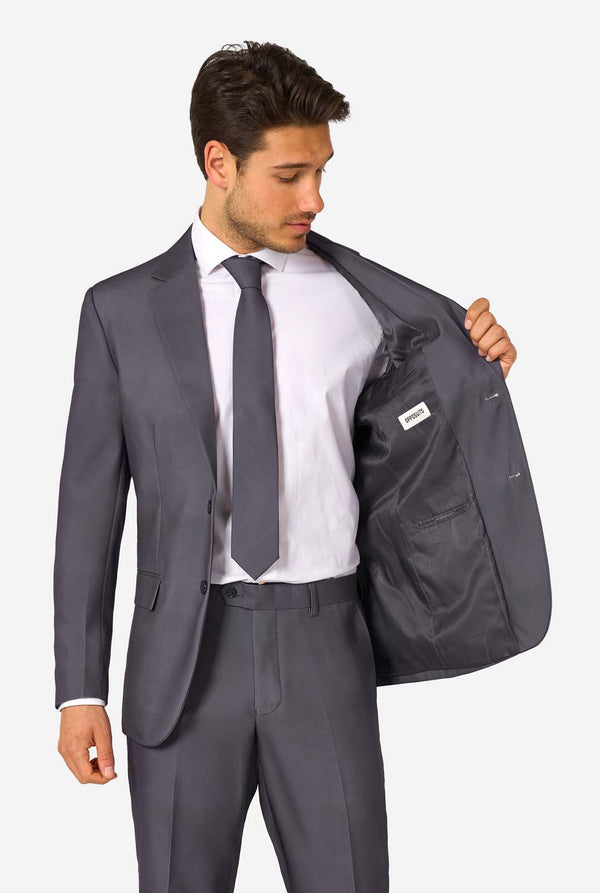 Man wearing a gray suit with a white shirt and tie, holding his jacket open.