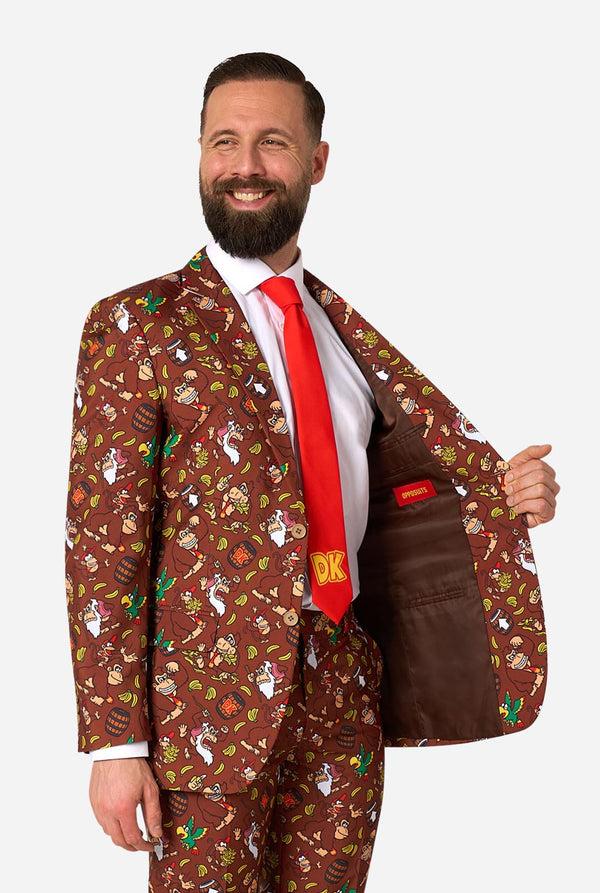 Man wearing a Donkey Kong patterned brown suit with a red tie on a white background