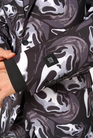 Close-up of a person wearing a blazer with a dark gray, black, and white Ghost Face pattern. The sleeve cuff is shown with a black button and a black fabric label that reads 'OPPOSUITS'.