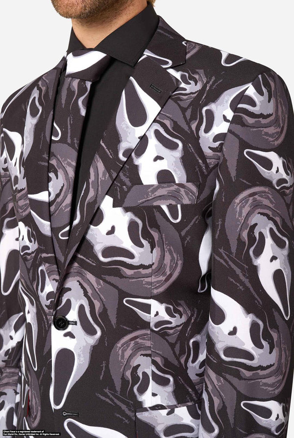 A man modeling a Ghostface-themed suit with a black, white, and gray mask pattern, a black shirt, a bow tie. Chest close-up.