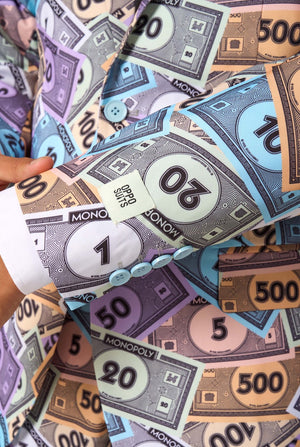 Roll of paper with colorful Monopoly money design held by a hand.