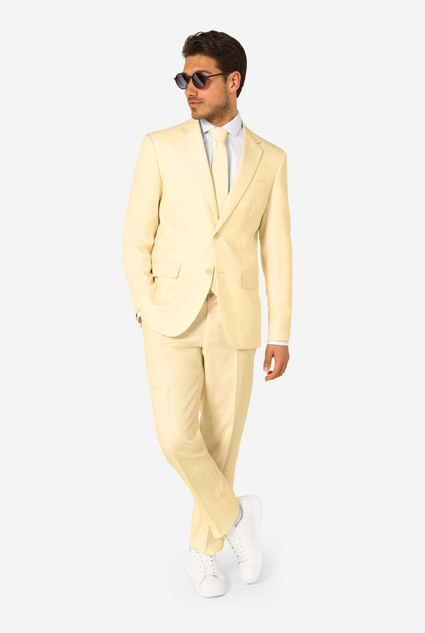 Man wearing a light yellow suit with sunglasses on a white background. Full body image