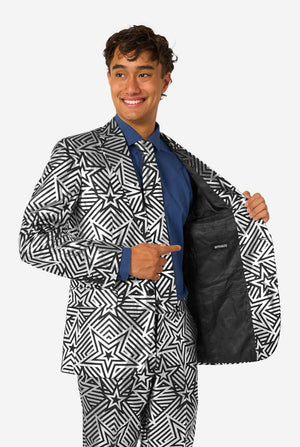 Man wearing a black and silver star patterned suit jacket over a blue shirt on a white background