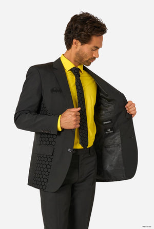 Man wearing a black Batman suit with a yellow shirt and black tie on a white background. 