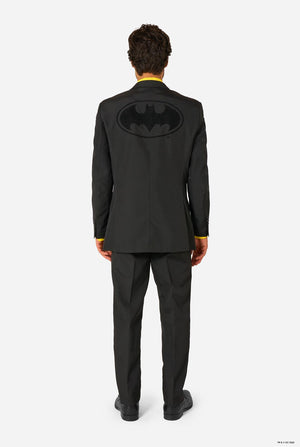 Person wearing a black suit with a Batman logo on the back, standing against a white background. View from the back