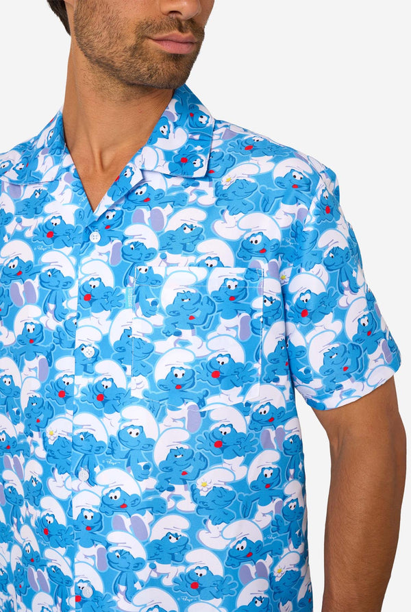 Man wearing a blue patterned shirt with smurf characters on a white background