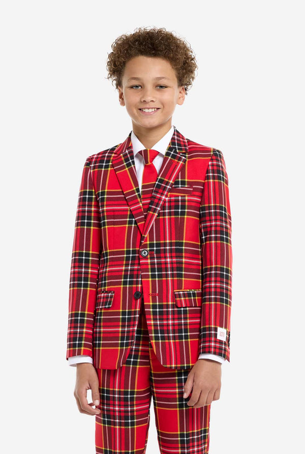 A young boy is wearing a stylish red plaid suit, known as The Lumberjack by OppoSuits. This teen boys' suit features a bold red, black, and yellow tartan pattern, perfect for holiday parties, formal events, or casual occasions that call for a playful yet classy look. The suit includes a matching jacket, trousers, and tie, all designed with a slim fit cut for a modern, youthful appearance. The boy pairs the suit with a crisp white shirt, enhancing the vibrant colors of the plaid pattern.