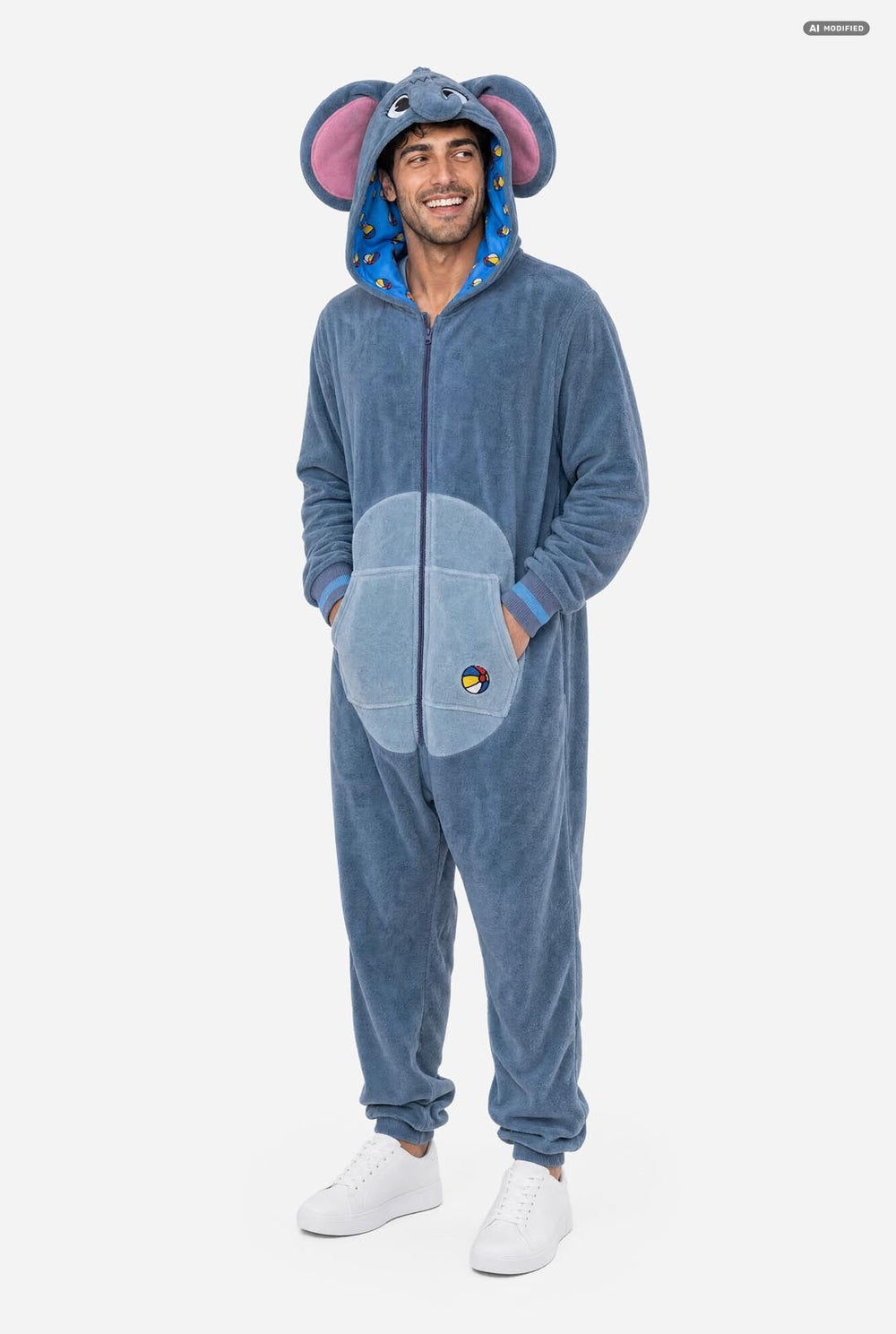 A man wearing a blue elephant onesie pajama with pink inner ears, a full front zipper, and a hood, standing against a light gray background.