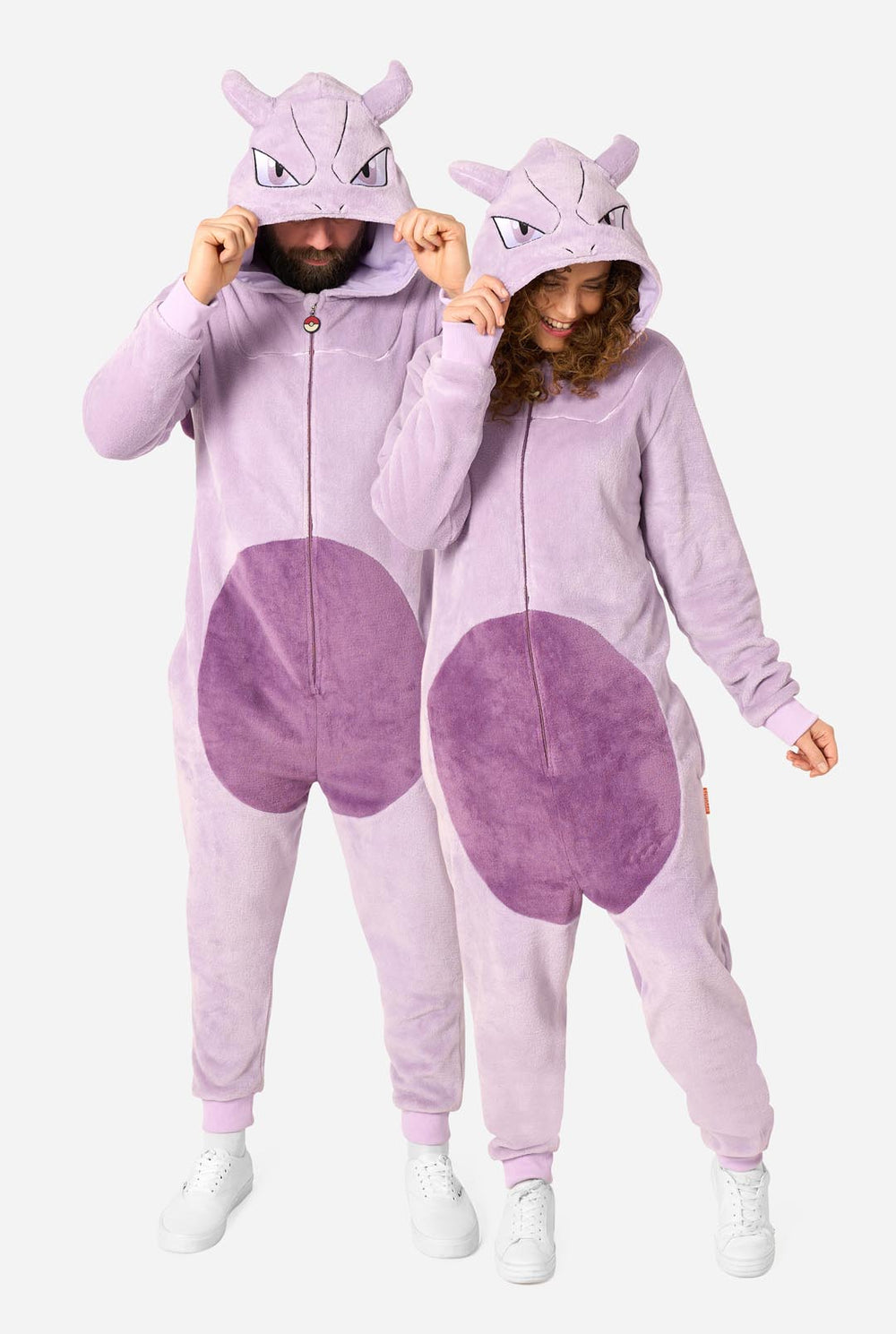 Two models wearing matching light purple and purple plush onesie pajamas with Mewtwo hood details, shown against a plain light gray background.