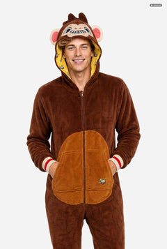 A man wearing a brown plush monkey onesie with a hood featuring a monkey face and pink ears, standing against a light gray background.