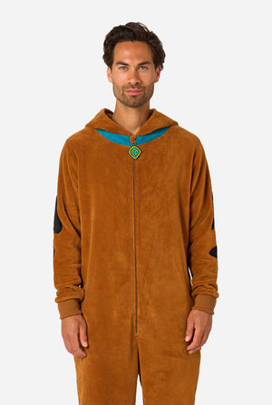 A person wearing a brown hooded onesie costume with a blue collar trim and black patch details, photographed against a light gray studio background.