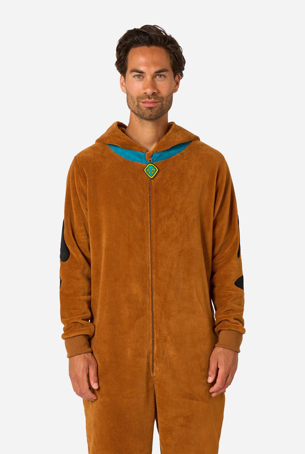 A person wearing a brown hooded onesie costume with a blue collar trim and black patch details, photographed against a light gray studio background.