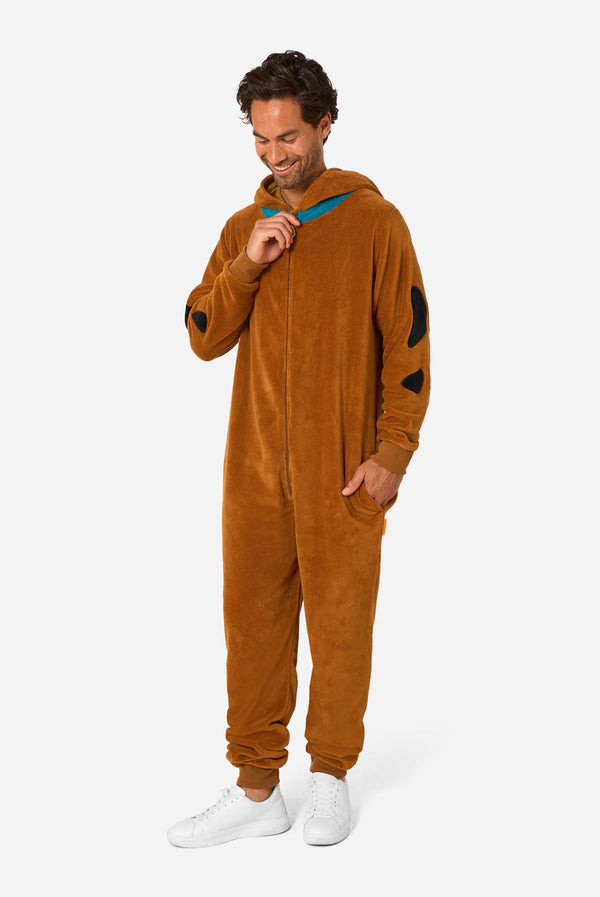A person wearing a brown hooded onesie costume with a blue collar trim and black patch details, with the hood down, photographed against a light gray studio background.