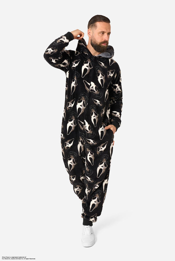 A man modeling a black hooded onesie covered in a white Ghost Face print, shown against a plain light gray studio background.