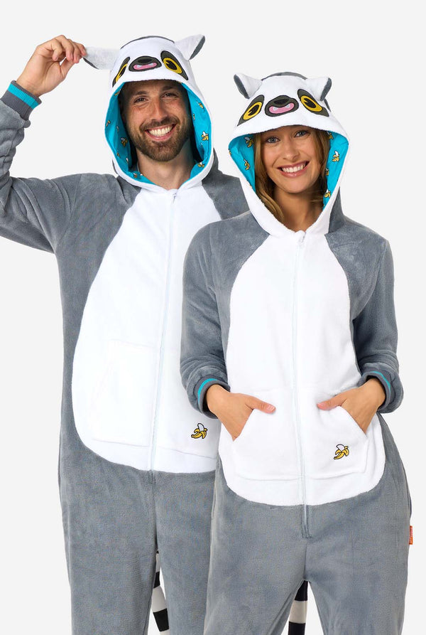 Two people wearing matching lemur-themed onesies on a white background