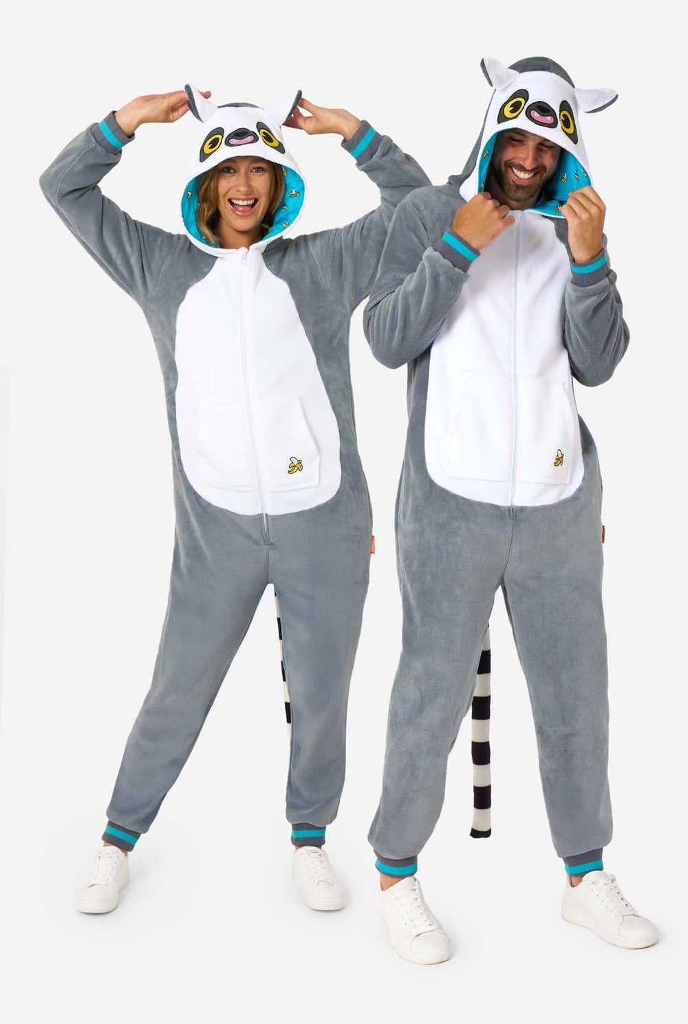 Two people wearing matching lemur-themed onesies on a white background