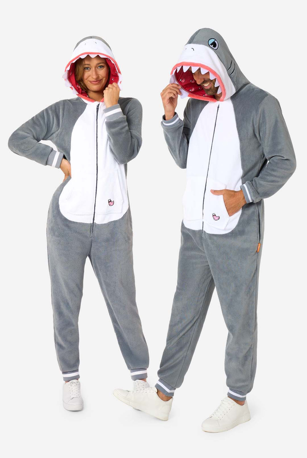 Two people wearing shark-themed onesies on a white background
