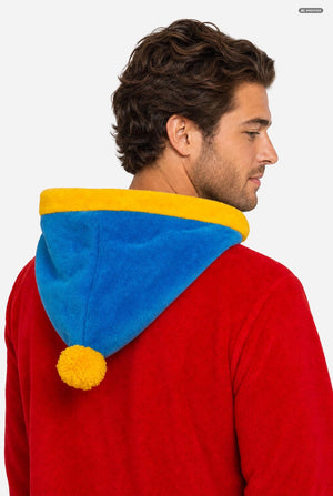 A man wearing a South Park Stan Onesie, red and brown hooded zip-up onesie pajama with a blue and yellow hood, yellow cuffs, a South Park patch on the sleeve, and brown pants, photographed against a light gray studio background. View form the back, hood close up.