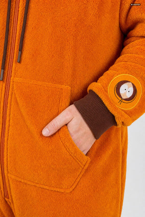 A smiling man wearing an orange South Park Kenny onesie with brown drawstrings and cuffs, standing against a light gray background. A small patch on the left leg reads 'South Park'. Sleeve close up.