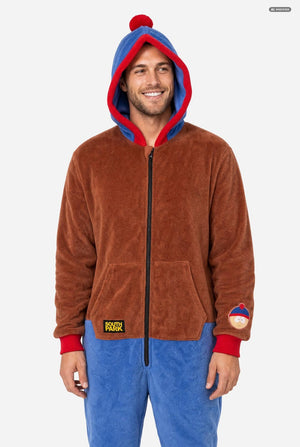 A man wearing a brown and blue South Park Stan onesie with blue and red hood lining, and a South Park patch on the sleeve, photographed against a light gray studio background.