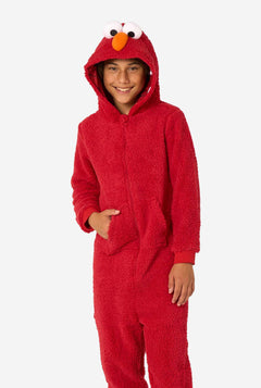 Kid is wearing a red onesie resembling Elmo. He has his right hand in his pocket.