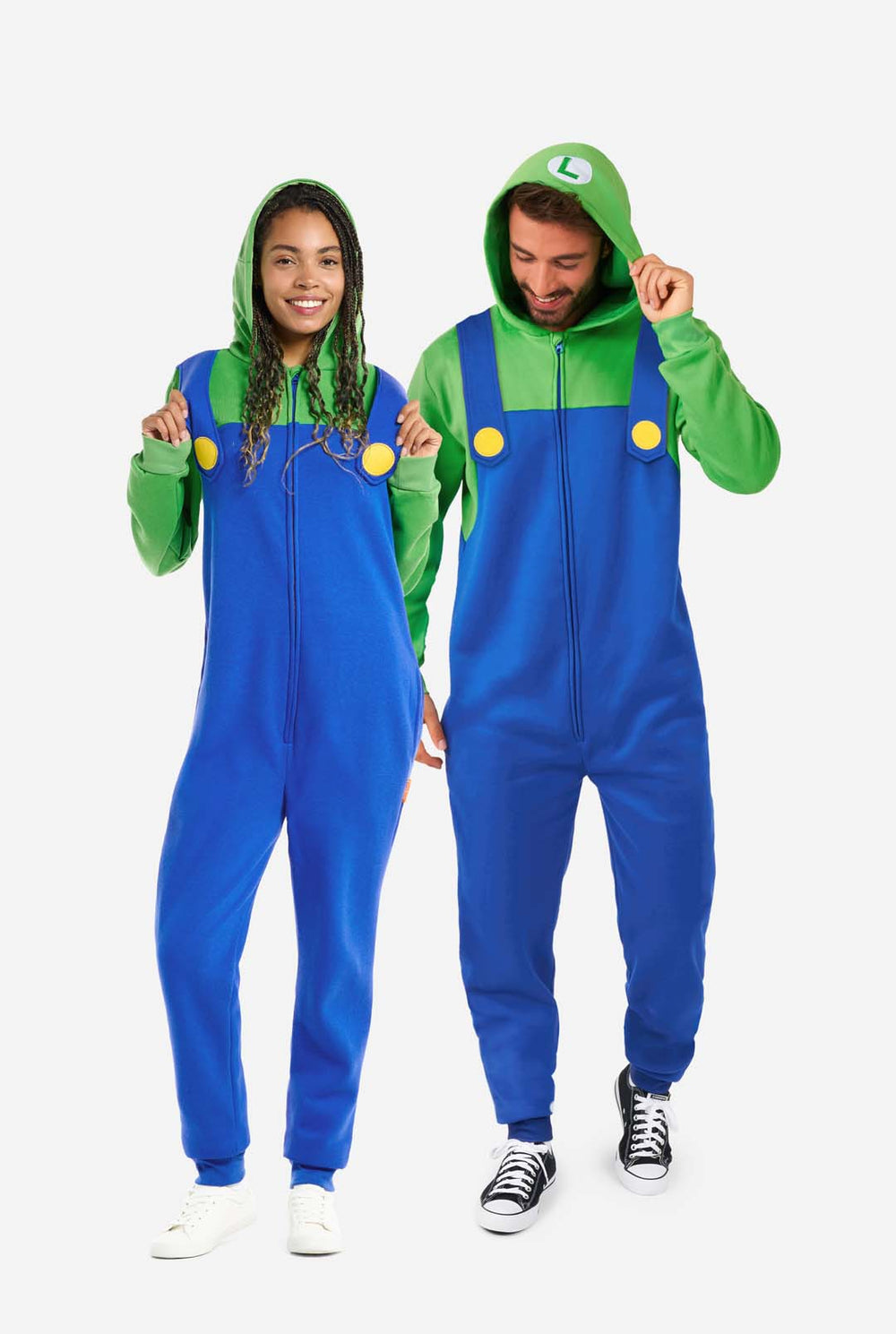 A man and a woman are dressed in a Luigi-themed onesie. The outfit looks as a bright green hoodie with an "L" symbol on the hood and blue overalls with large yellow buttons on the straps. The overall design mimics the look of the popular video game character Luigi, with contrasting green and blue colors. The background is plain, putting focus on the costume.