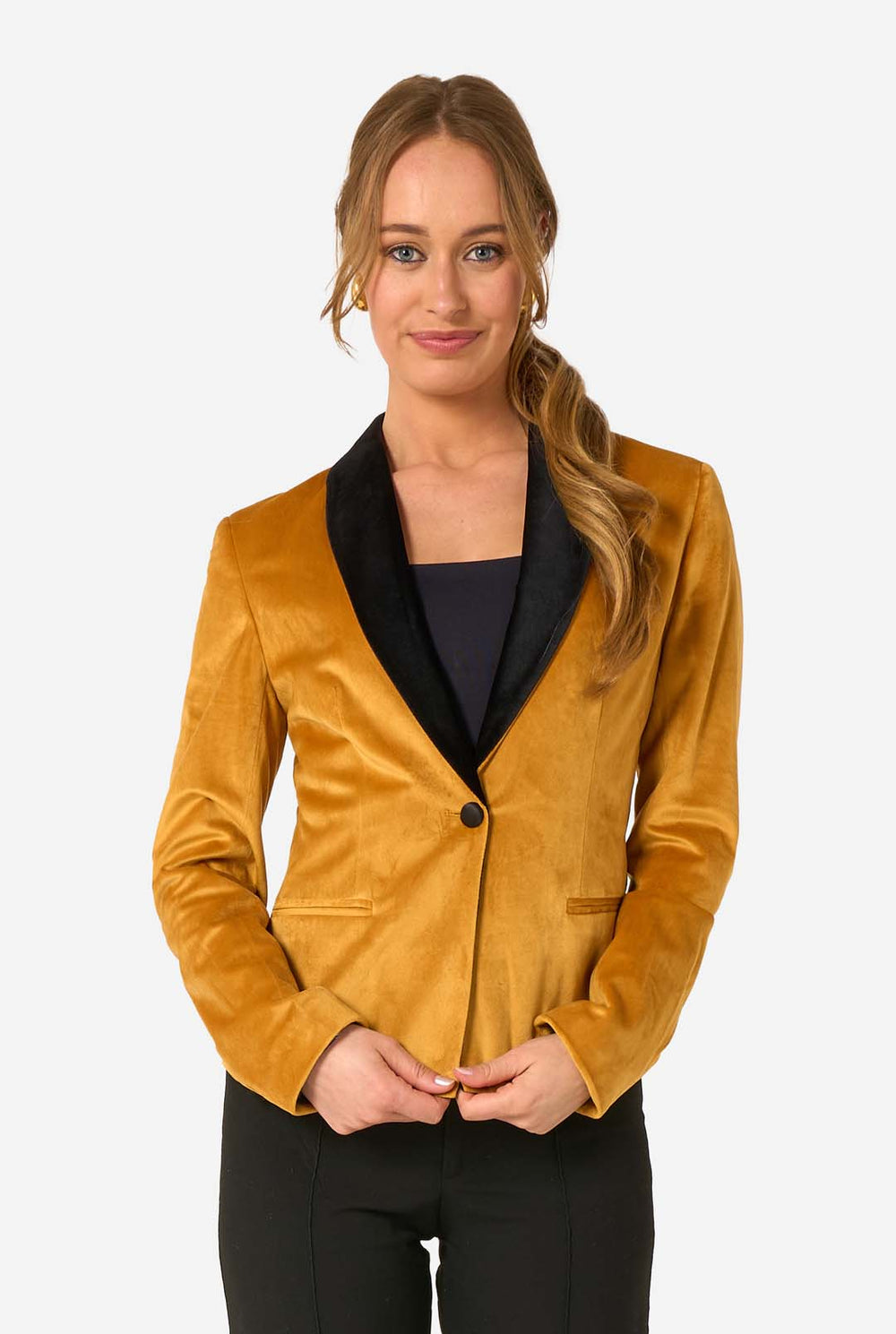 Woman wearing a velvet golden blazer with black lapels on a white background
