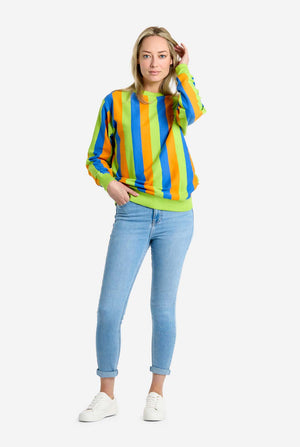 Woman wearing a colorful striped Bert sweater and light blue jeans on a white background. Full body image