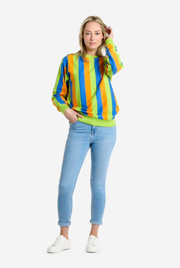 Woman wearing a colorful striped Bert sweater and light blue jeans on a white background. Full body image