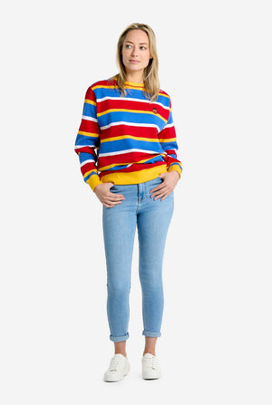 Person wearing a colorful striped Ernie sweater and light blue jeans on a white background. Full body image