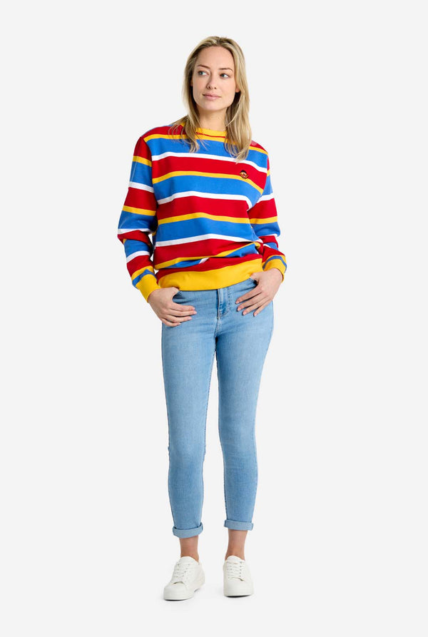 Person wearing a colorful striped Ernie sweater and light blue jeans on a white background. Full body image