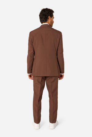 Man wearing a brown suit standing against a white background. View from the back
