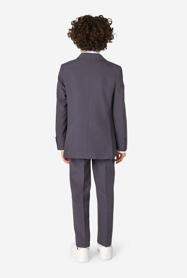 A child model shown from the back wearing a dark gray two-piece suit with white sneakers, photographed against a clean white studio background.